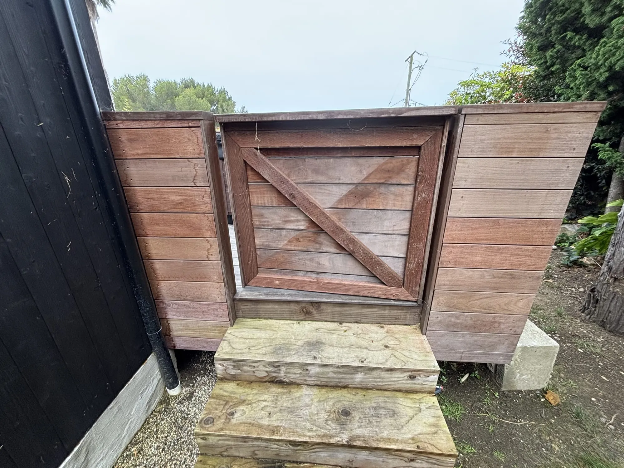 The same gate and fence after restoration, cleaned and sealed to an even brown