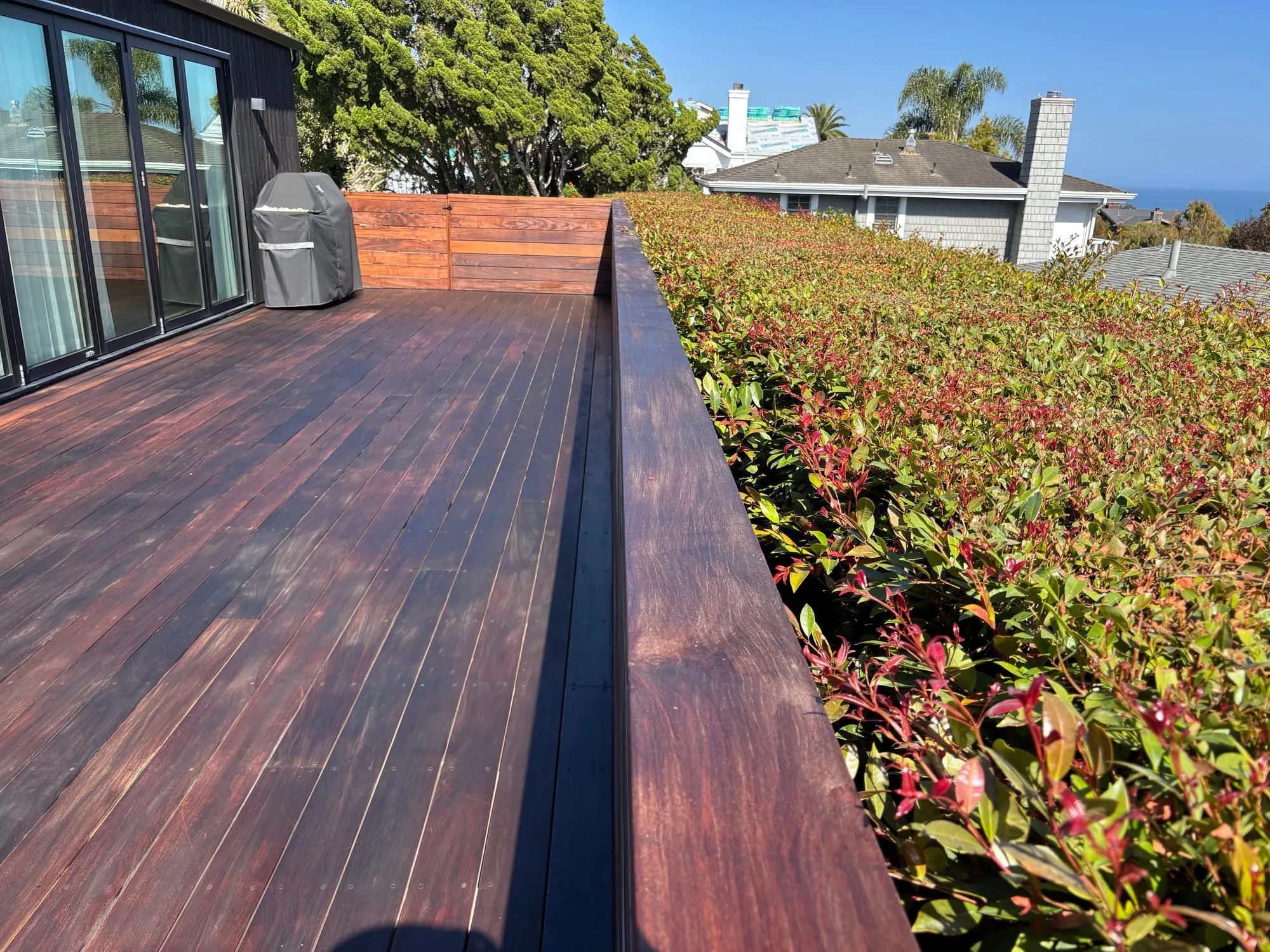 The same rooftop deck after restoration, oiled to a rich reddish-brown with an ocean view