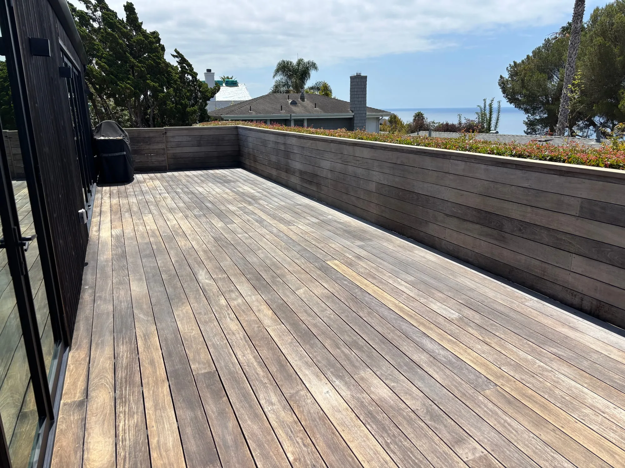 A rooftop deck before restoration, the ipe boards weathered to a flat gray